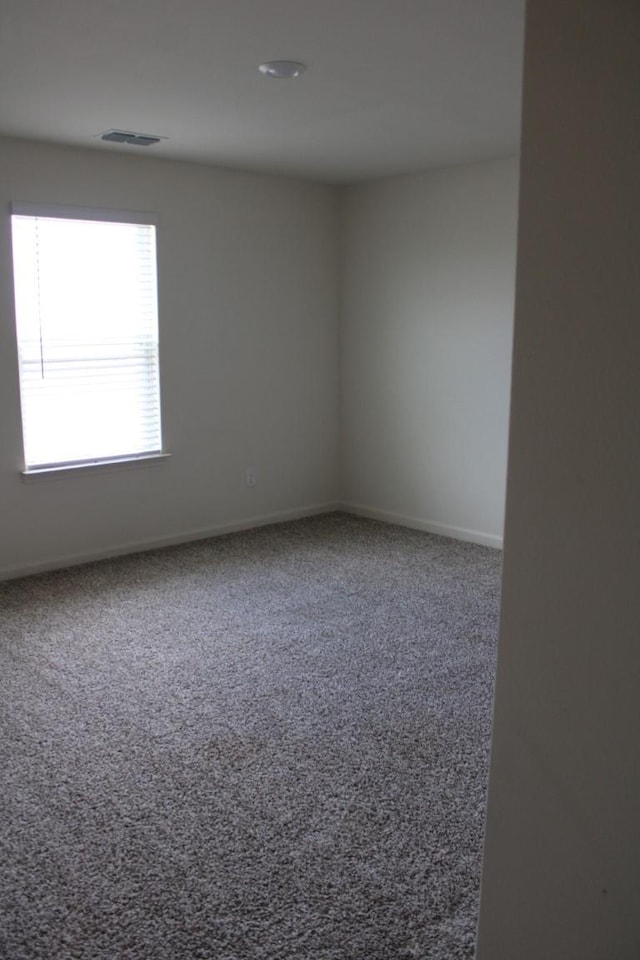 carpeted empty room featuring baseboards and visible vents