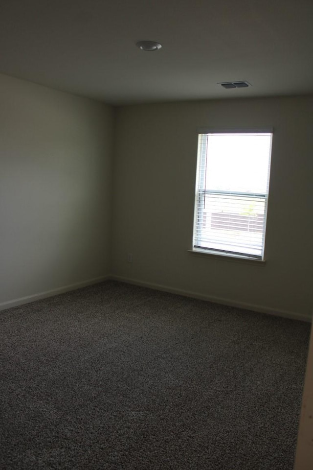 carpeted spare room with visible vents and baseboards