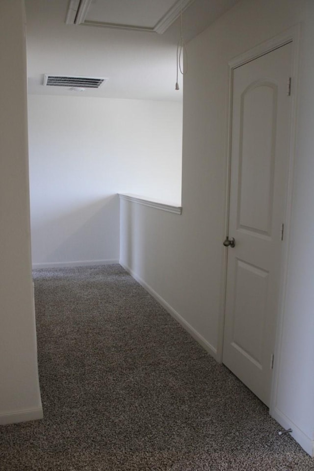 carpeted spare room with attic access, visible vents, and baseboards