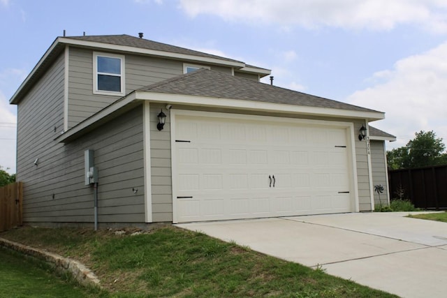 view of side of property featuring concrete driveway, an attached garage, and fence