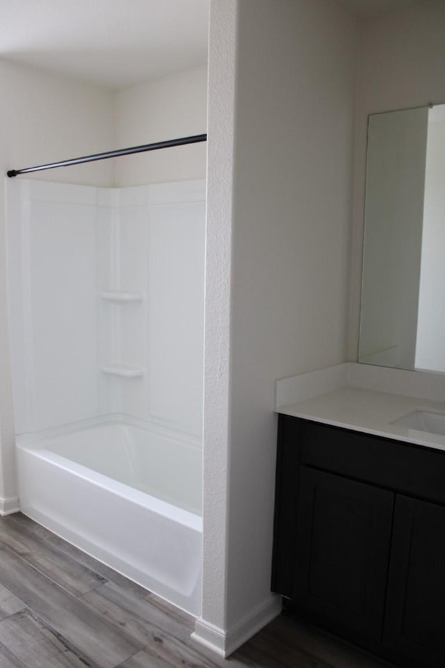 full bathroom with washtub / shower combination, vanity, baseboards, and wood finished floors