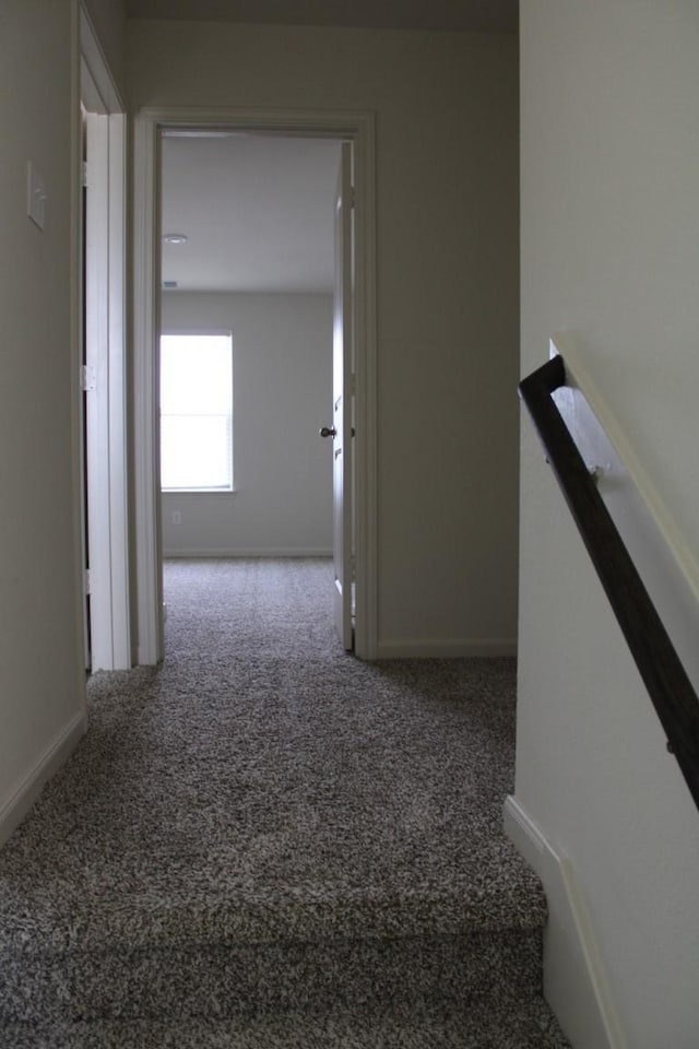 hallway featuring carpet and baseboards