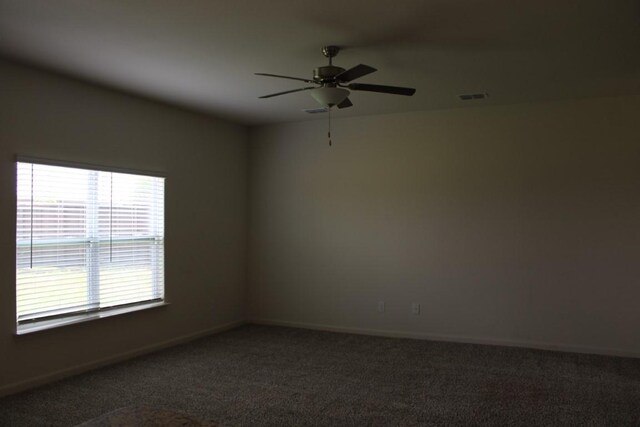 unfurnished room featuring ceiling fan, visible vents, dark carpet, and baseboards