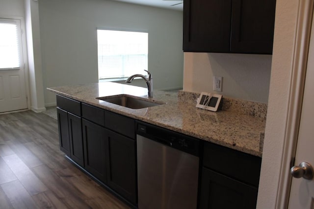 kitchen featuring light wood finished floors, stainless steel dishwasher, a sink, and a wealth of natural light