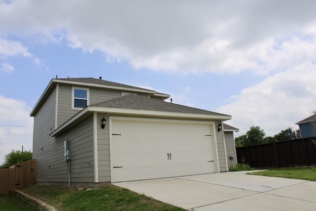 view of home's exterior with driveway, an attached garage, and fence