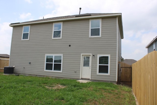 back of property with a fenced backyard, a yard, and central AC