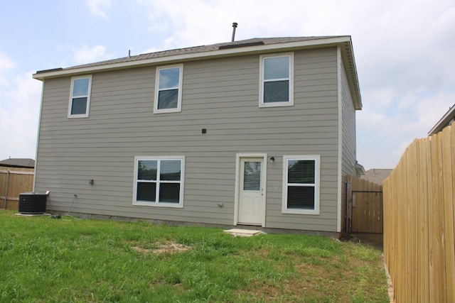 rear view of property with a fenced backyard, cooling unit, and a lawn