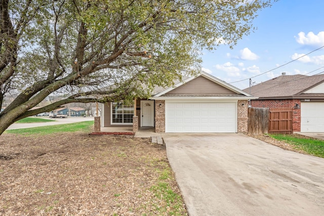 single story home with a garage, concrete driveway, brick siding, and fence