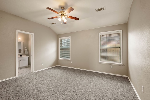 unfurnished bedroom with lofted ceiling, baseboards, visible vents, and light colored carpet