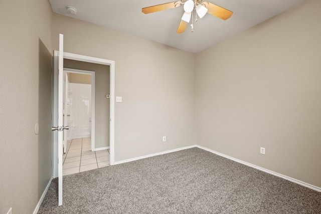 tiled empty room with carpet, ceiling fan, and baseboards