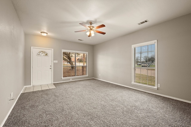 carpeted spare room with baseboards, visible vents, and a ceiling fan