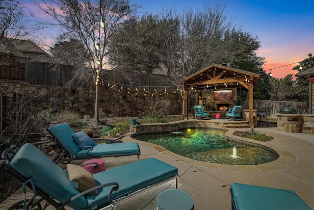 view of patio / terrace with a gazebo, an outdoor stone fireplace, and a fenced backyard