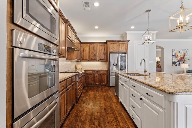 kitchen featuring dark wood-style floors, visible vents, a sink, ornamental molding, and stainless steel appliances