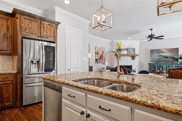 kitchen featuring a sink, a stone fireplace, ornamental molding, stainless steel appliances, and backsplash