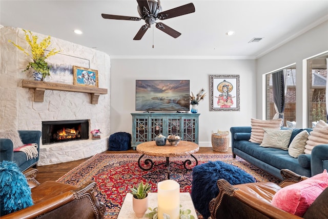 living room featuring visible vents, wood finished floors, a fireplace, and ornamental molding