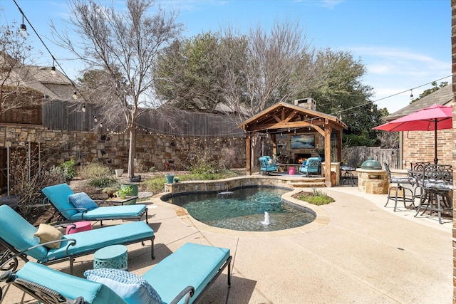 view of pool with a gazebo, a patio, a fenced backyard, and an outdoor stone fireplace