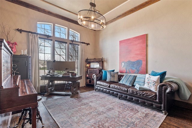 living area with crown molding, a notable chandelier, and wood finished floors