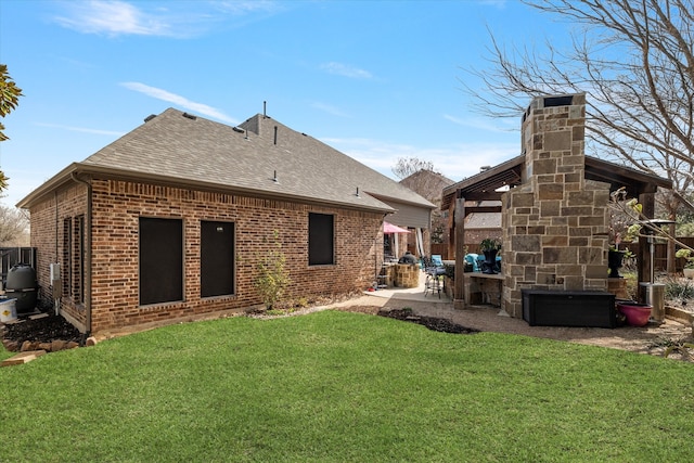 back of house with brick siding, a shingled roof, fence, a lawn, and a patio area