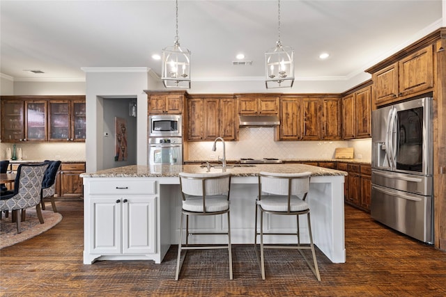 kitchen with a breakfast bar, under cabinet range hood, a sink, dark wood finished floors, and appliances with stainless steel finishes