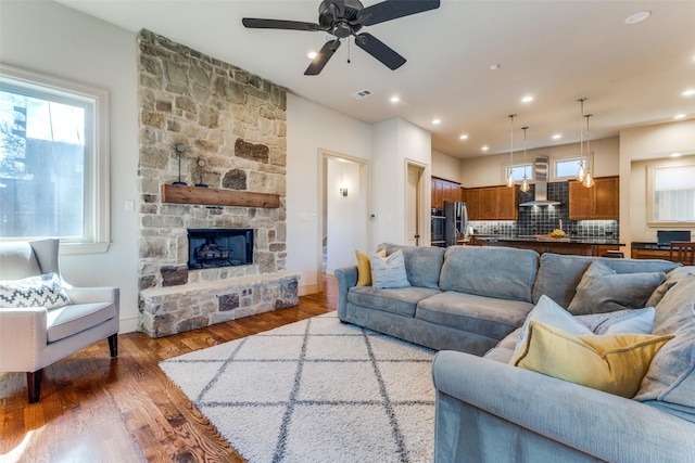 living area featuring recessed lighting, visible vents, wood finished floors, and a stone fireplace