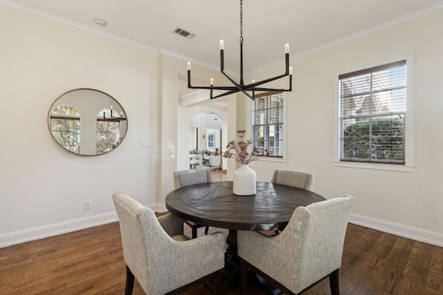 dining area featuring baseboards, visible vents, arched walkways, wood finished floors, and crown molding