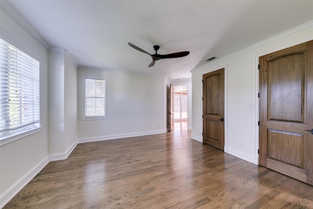 unfurnished bedroom featuring multiple windows, visible vents, wood finished floors, and ornamental molding