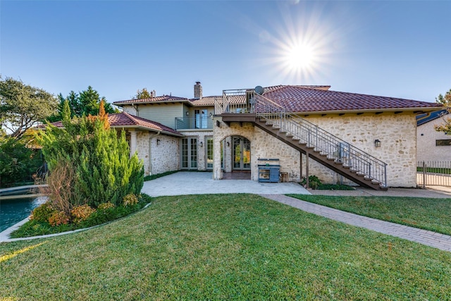 back of property with a tiled roof, french doors, a yard, and stairway