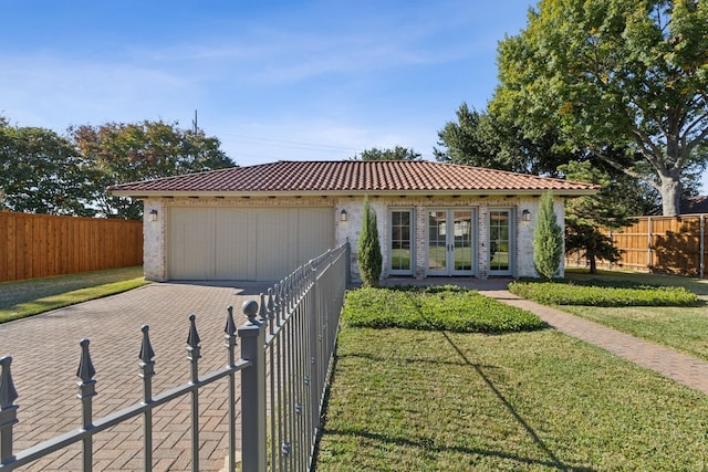 view of front facade with a garage, a tiled roof, french doors, decorative driveway, and a front yard