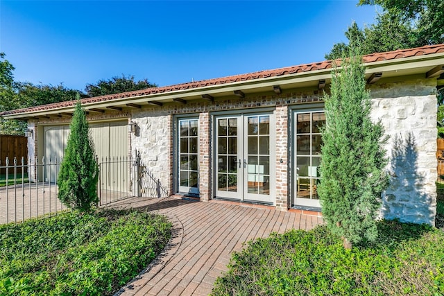 back of house with french doors, a tile roof, fence, and a deck