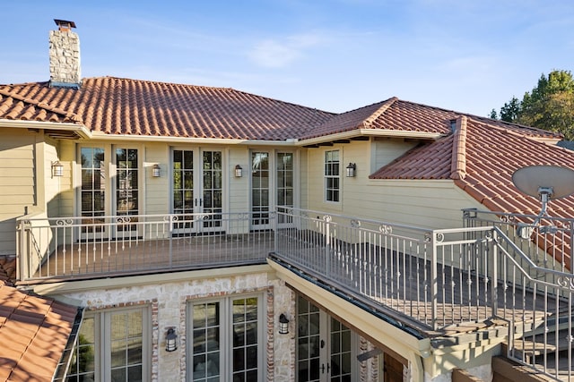 back of house with a tiled roof, french doors, and a chimney