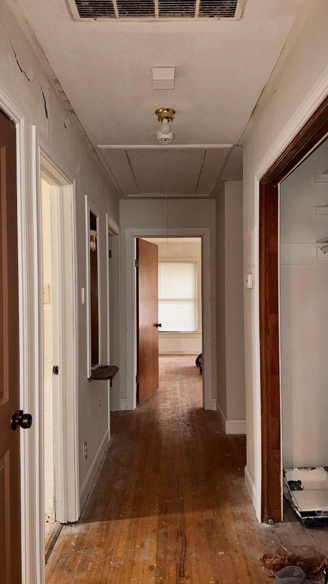 hall with attic access, baseboards, and hardwood / wood-style floors