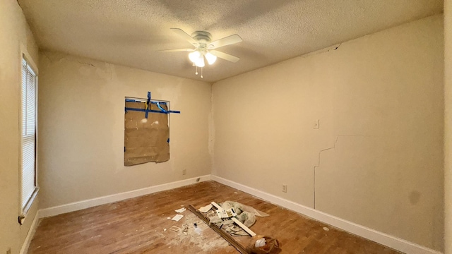 empty room featuring ceiling fan, a textured ceiling, baseboards, and wood finished floors