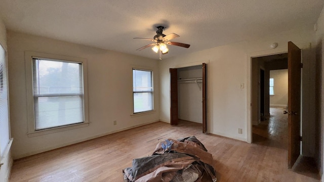 unfurnished bedroom with a ceiling fan, light wood-style flooring, baseboards, and a closet