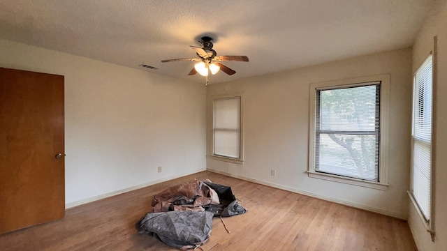 empty room with baseboards, a textured ceiling, visible vents, and wood finished floors