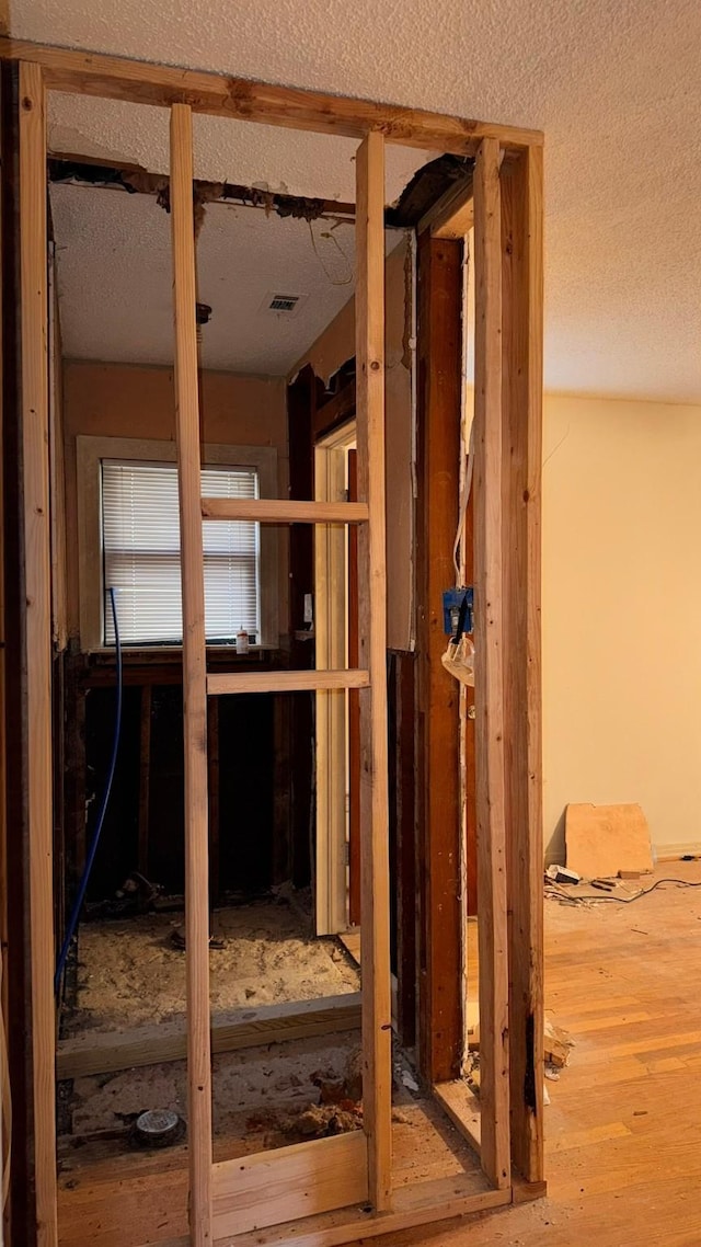 interior space featuring visible vents, a textured ceiling, and wood finished floors