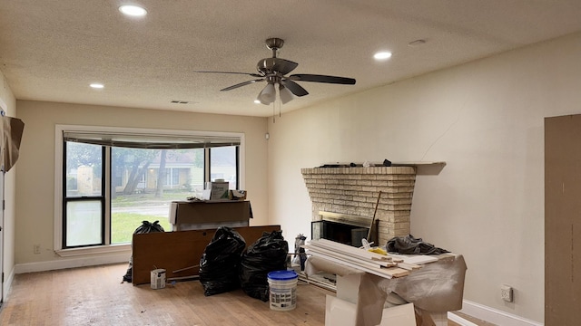 home office with recessed lighting, a brick fireplace, a textured ceiling, wood finished floors, and baseboards