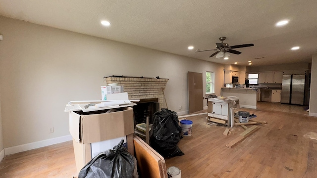 miscellaneous room with light wood-style floors, a brick fireplace, baseboards, and recessed lighting