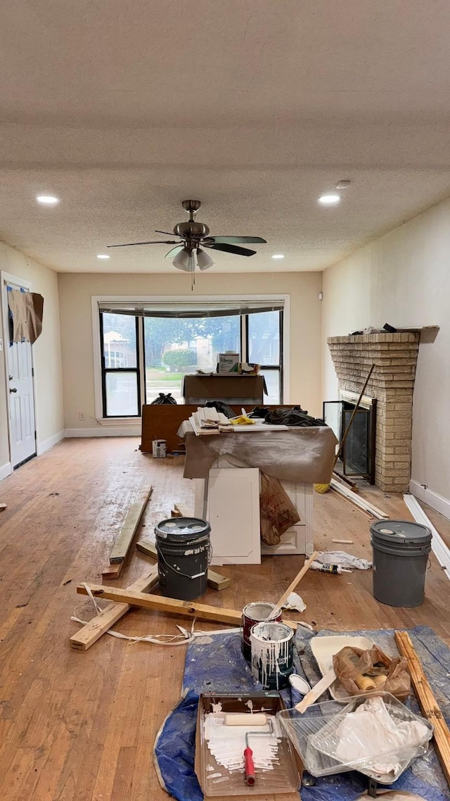 interior space with wood-type flooring, a fireplace, baseboards, and a textured ceiling