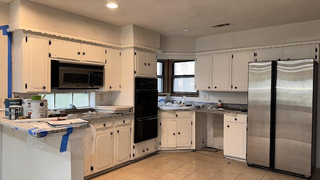 kitchen featuring light tile patterned floors, visible vents, white cabinets, a peninsula, and black appliances