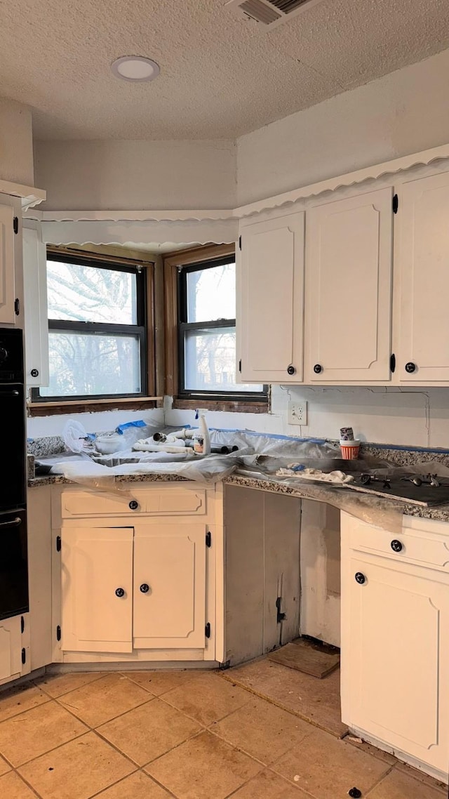 kitchen featuring dobule oven black, visible vents, white cabinets, and a textured ceiling