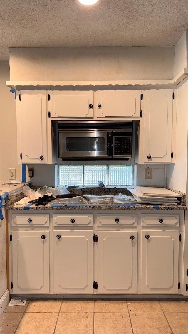 kitchen with light tile patterned floors, white cabinetry, and a textured ceiling