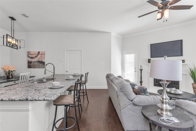 living area with dark wood-style floors, visible vents, ornamental molding, baseboards, and ceiling fan with notable chandelier