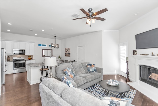 living area featuring recessed lighting, dark wood-style flooring, visible vents, and a fireplace with raised hearth