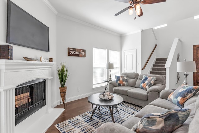 living room with a fireplace with raised hearth, baseboards, wood finished floors, and crown molding