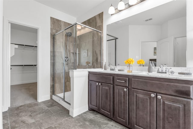 full bathroom with a sink, double vanity, a shower stall, and visible vents