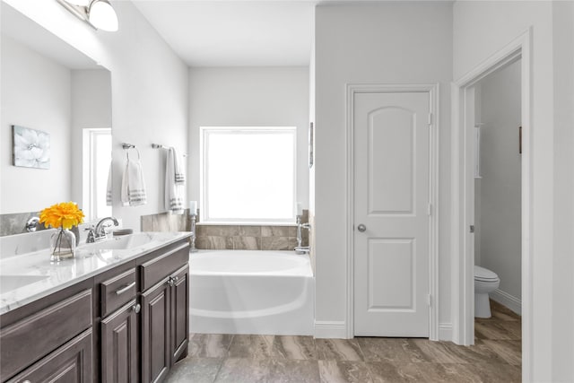 bathroom with a garden tub, a sink, toilet, and double vanity