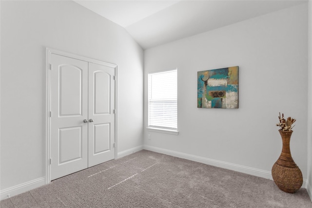 carpeted bedroom with vaulted ceiling, a closet, and baseboards