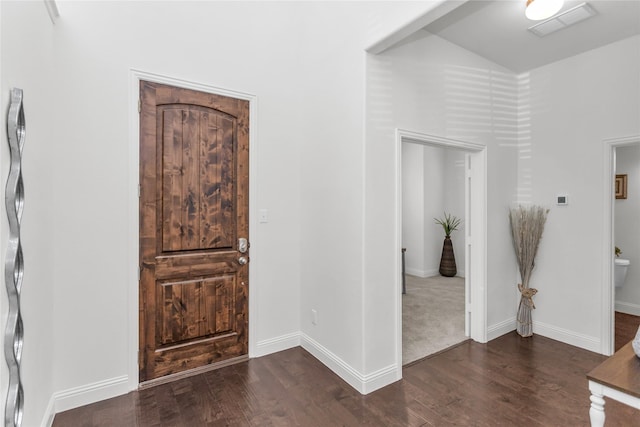 entryway with baseboards, visible vents, vaulted ceiling, and wood finished floors