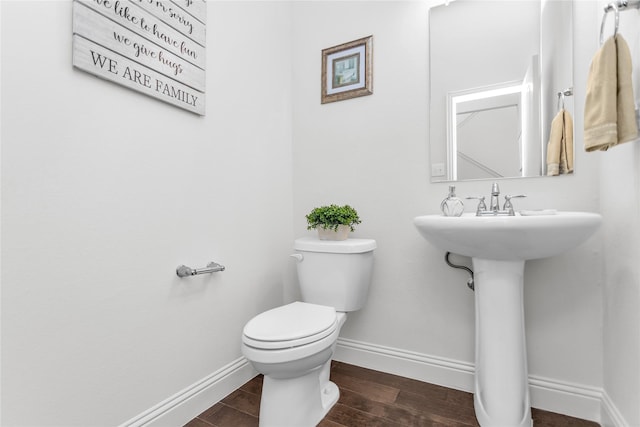 bathroom with toilet, baseboards, and wood finished floors