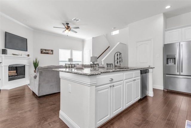 kitchen featuring stainless steel appliances, dark wood-type flooring, visible vents, open floor plan, and light stone countertops